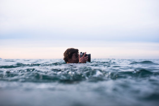Photographer swimming in the ocean to photograph waves in Spain