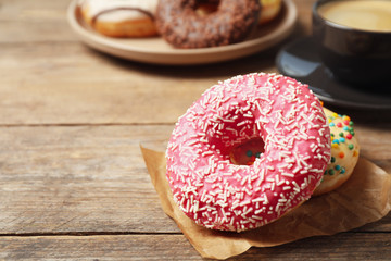 Delicious glazed donuts on wooden table, closeup. Space for text