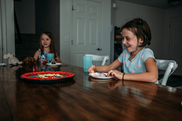 side view of a girl smiling at her birthday cake at a party