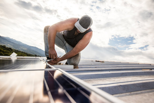 construction worker installs solar panels on rooftop.