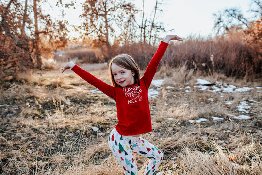 Young girl dancing in field in christmas leggings and shirt