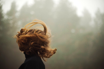 woman standing by forest in foggy weather