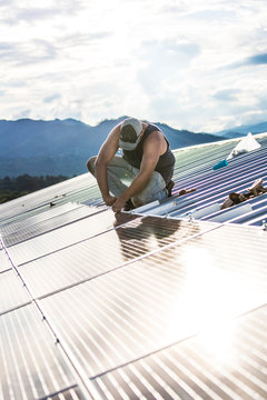 Worker installs solar panels on roof of building.