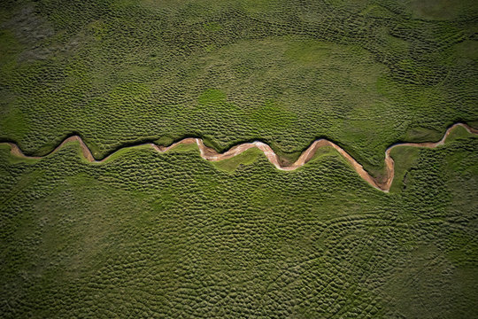 Dry river geometrically flowing in green field