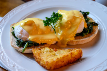 Weekend vegetarian brunch in Scotland with two eggs benedict on homemade muffuns with spinach and yellow hollandaise sauce.