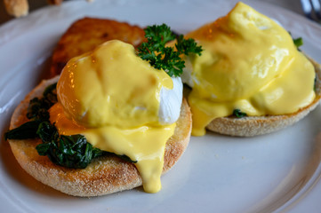 Weekend vegetarian brunch in Scotland with two eggs benedict on homemade muffuns with spinach and yellow hollandaise sauce.