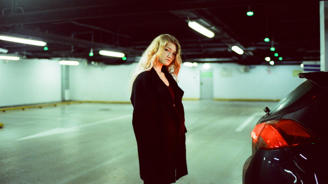 Portrait of a woman standing in an underground parking near a car
