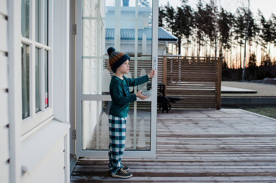 boy standing at his back door holding a cereal bowl looking outside