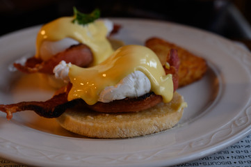 Weekend brunch in Scotland with two eggs benedict on homemade muffuns with roasted bacon and yellow hollandaise sauce.