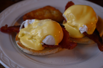 Weekend brunch in Scotland with two eggs benedict on homemade muffuns with roasted bacon and yellow hollandaise sauce.