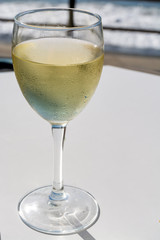 Summer holiday on sea, drinking white wine on outdoor terrace with sea view in sunny day