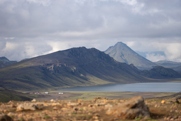 Fototapeta premium View on Hvanngil mountain hut and camp site with green hills, river stream and lake. Laugavegur hiking trail, Iceland