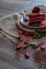 Red Velvet cake on a blue plate with strawberries and pure cocoa with a rustic background with flowers and cloth napkins