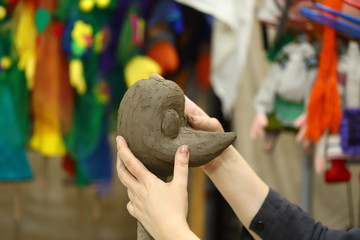 The artist, a master ceramist, sculpts the clay head of a doll for the performance of a puppet theater. Concept of children's theater, art.