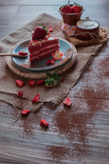 Red Velvet cake on a blue plate with strawberries and pure cocoa with a rustic background with flowers and cloth napkins