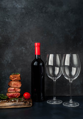 four types of frying meat, rare, medium, medium well, well  done  and  a bottle of wine and two glasses a stone background