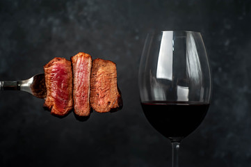 Three types of frying meat, rare, medium, well done on a fork and glass of wine on a stone...