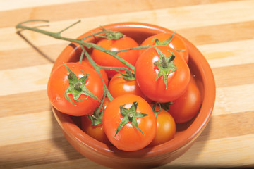 tomates cherry en rama recien recogidos en mader y vasija de barro