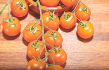 tomates cherry en rama recien recogidos en mader y vasija de barro