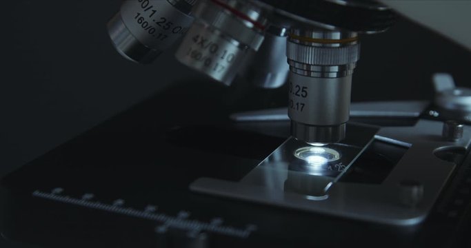Crop closeup shot of microscope in the laboratory, scientist is conducting study examines the sample on a slide