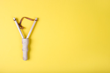 Wooden slingshot on a yellow background. Top view with copy space, flat lay.