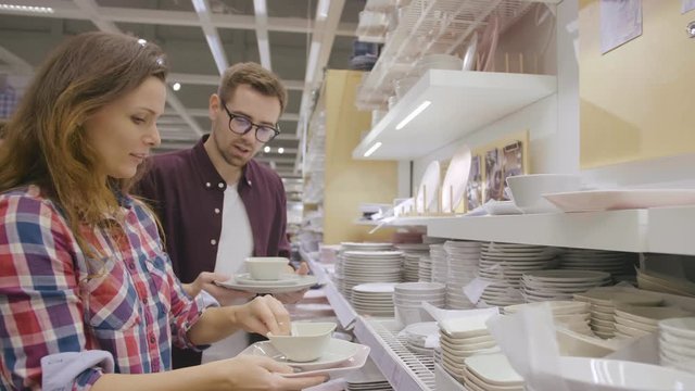 Young couple choosing plates in houseware store
