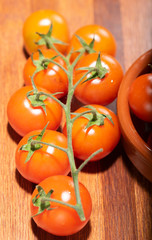 tomates cherry en rama recien recogidos en mader y vasija de barro