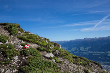 Hiking on the Hafelekar in Tyrol, Austria with Innsbruck and the Inn Valley in the background. Also the trail is marked with a stone colored like the austrian flag.