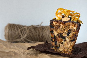 A delicious cake of dried fruits and nuts, covered with chocolate icing and candied fruit with orange on craft paper.