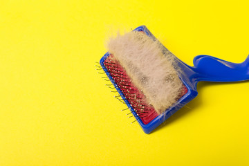 Comb for animal hair and gray wool on a yellow background. Animal hairbrush.