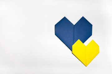 Blue paper heart under smaller yellow paper heart, origami art, on white isolated background....