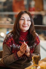 Nice Asian young woman wiping her nose and having a cup of tea after shopping in a cafe