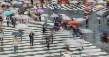 Blurred people walking on Shibuya crossing in Tokyo, Japan. Crowded street with umbrellas.