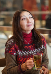 Nice Asian young woman wiping her nose and having a cup of tea after shopping in a cafe