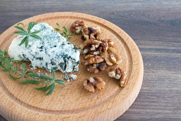 Blue cheese on a wooden serving board with walnuts