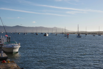 Fototapeta na wymiar Tranquil winter day scene at Morro Bay with boats and mountains and blu sky shortly before sunset