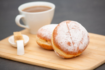 Dessert, Donuts, chocolate and strawberry circles, sugar and cream on Donuts and hot coffee cups, preparation for a break or party on the wooden table background.