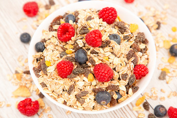 Breakfast Served in the morning with corn flakes Whole grains and raisins with milk in cups and Strawberry, Blueberry, Raspberry, Kiwi on the wood table,Diet food or healthy food in the morning.