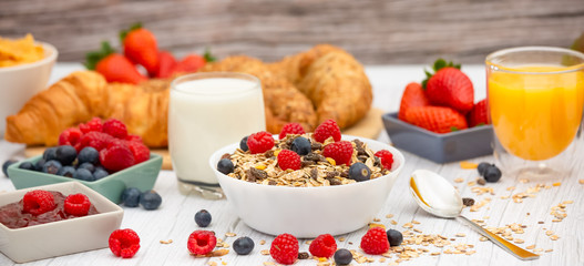 Breakfast Served in the morning with Butter croissant and corn flakes Whole grains and raisins with milk in cups and Strawberry, Blueberry, Raspberry, Kiwi, Fresh Orange Juice on the breakfast table.