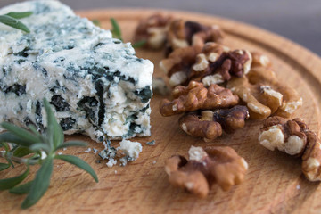 Blue cheese on a wooden serving board with walnuts