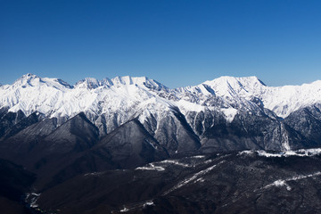 Fototapeta na wymiar A mountain range covered with snow against a blue sky Caucasus mountains