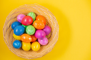 Beautiful group Easter eggs in the spring of easter day, red eggs, blue, purple and yellow in Wooden basket on the Yellow background