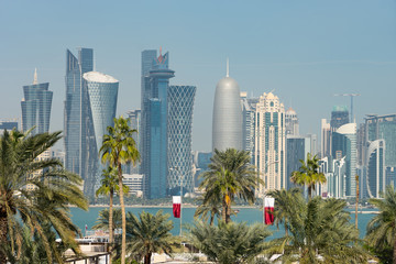 Fototapeta na wymiar Panoramic view of modern skyline of Doha through blurred palm trees. Qatar on sunny day