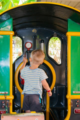 A little boy of three years rides in a children's train in the Riviera amusement park