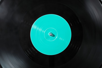 Black vinyl record on a DJ turntable. Black vinyl background with green label screen in the center....