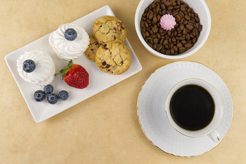 Hot coffee cup and breakfast baked on wooden board. Cup of tasty coffee with tasty cookies, on beige background. americano coffee and cookies with white berries. White Coffee Cup.