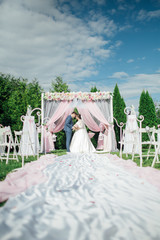Wedding day.  Happy Newlywed woman and man embracing. Beautiful wedding  for the bride and groom. Away wedding ceremony. Wedding place sitting with chairs for guests.