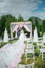 Wedding day.  Happy Newlywed woman and man embracing. Beautiful wedding  for the bride and groom. Away wedding ceremony. Wedding place sitting with chairs for guests.