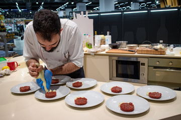 Chef arranging plates with steak tartare before serving. Selective focus. Restaurant and fine dining concept.
