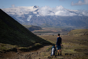 Backside of tall caucasian backpacker standing in over mountain and fog background on the Laugavegur hiking trail. Iceland